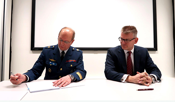 Insinöörikenraalimajuri Kari Renko allekirjoittaa F-35 -hankintasopimuksia pöydän ääressä oikealla puolellaan kaupallinen johtaja Lars-Christian Schauman.