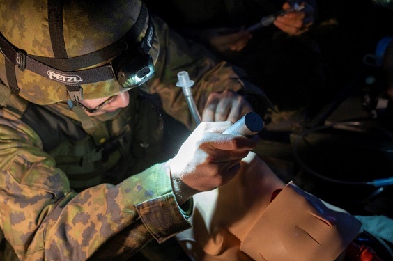 Maastopukuinen sotilas harjoittelee lääkintätoimenpiteitä potilasnukella