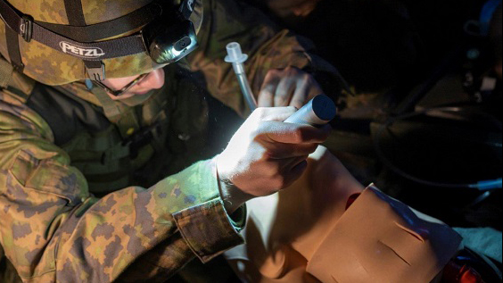 Maastopukuinen sotilas harjoittelee lääkintätoimenpiteitä potilasnukella