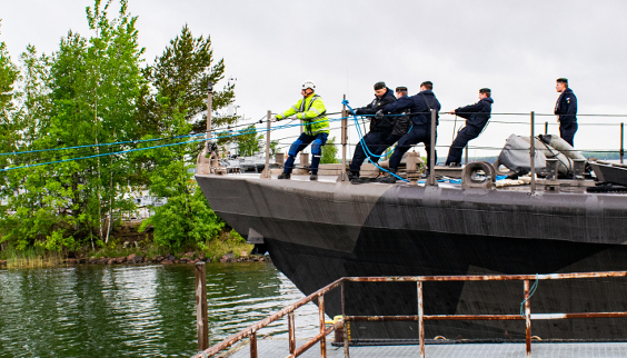 Marinsoldater och en anställd vid ett partnerföretag på fördäcket till ett stridsfartyg. Foto Millog Oy.