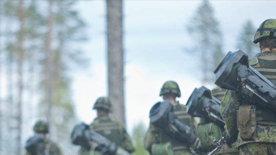 Soldiers wearing helmets walking in file carrying anti-tank weapons on their backs. Photo by Finnish Defence Forces.