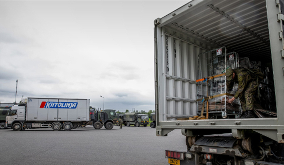 Rekkoja logistiikkakeskuksessa. Maastopukuinen sotilas kiinnittää rekan tavaratilassa rullakkoa. Kuva Puolustusvoimat.