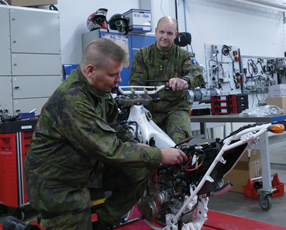 Two soldiers in combat uniforms doing maintenance on a motorcycle. Photo by Finnish Defence Forces.