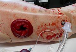 En patientsimulatordockas arm med ett blödande skottsår. Bild Försvarsmakten.
