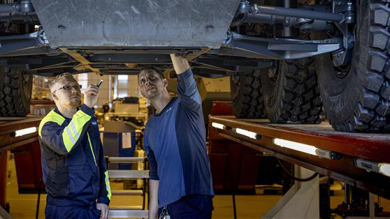 Kuvituskuva, jossa kaksi Patrian mekaanikkoa tarkistavat miehistönkuljetusajoneuvon alustaa.